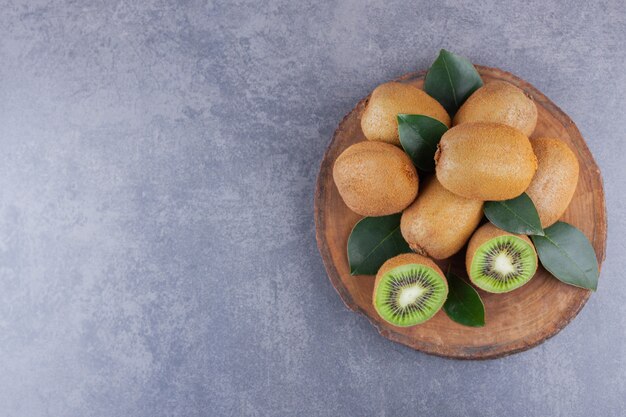 Whole and sliced kiwi fruit placed on a stone table.