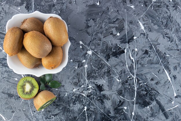 Free photo whole and sliced kiwi fruits in a glass board.