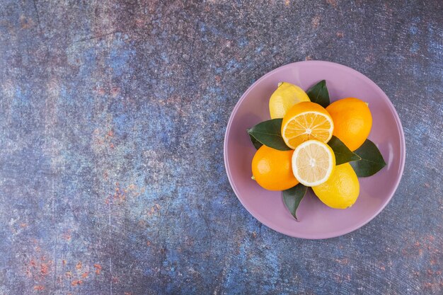 Whole and sliced lemon fruits placed on a stone .