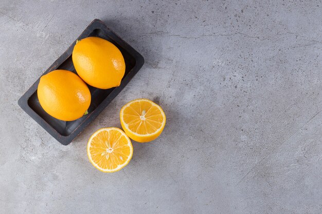 Whole and sliced lemons placed on black board