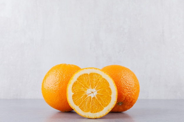 전체 및 슬라이스 오렌지 과일은 돌 테이블에 배치됩니다.