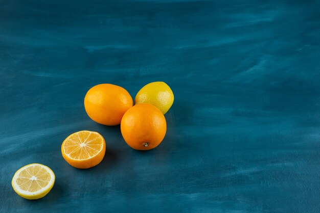 Whole and sliced ripe lemons placed on marble surface.