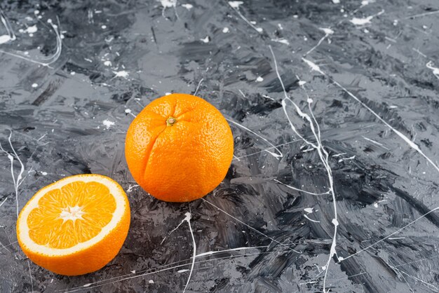 大理石の表面に置かれた全体とスライスされた熟したオレンジ。