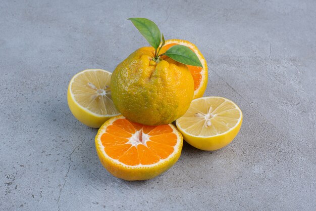 Whole tangerine on lemon and tangerine slices on marble background. 