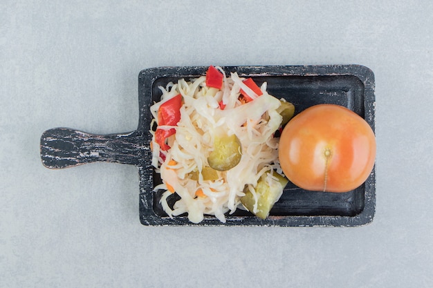 Whole tomatoes and sauerkraut on the board    