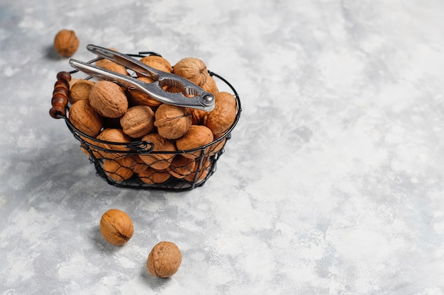 Whole walnuts in shell in food metal basket, walnut kernels. Top view on concrete 