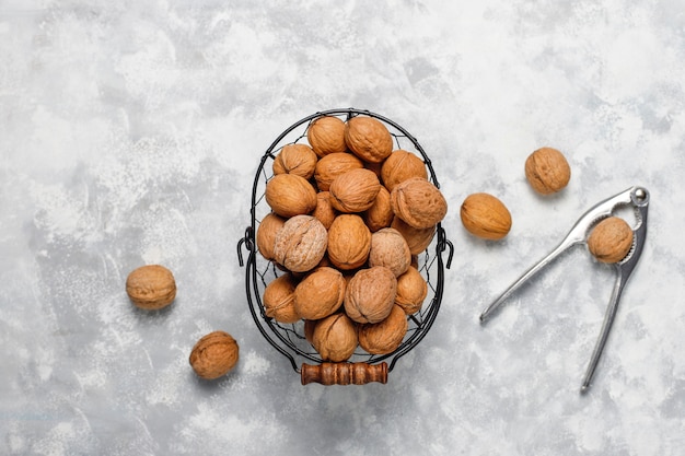 Free photo whole walnuts in shell in food metal basket, walnut kernels. top view on concrete