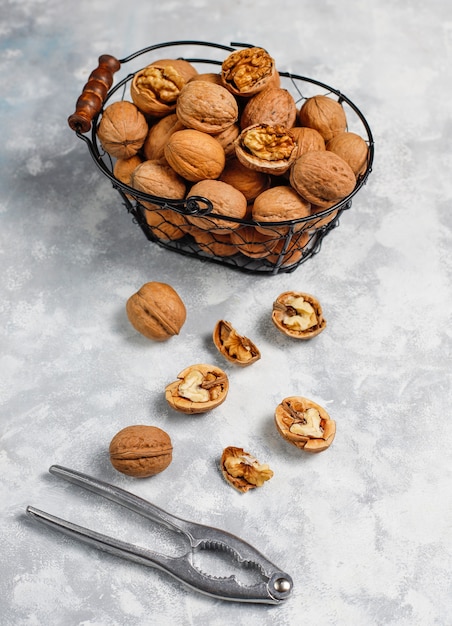 Free photo whole walnuts in shell in food metal basket, walnut kernels. top view on concrete