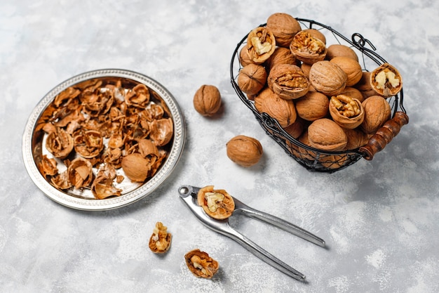 Whole walnuts in shell in food metal basket, walnut kernels. Top view on concrete 