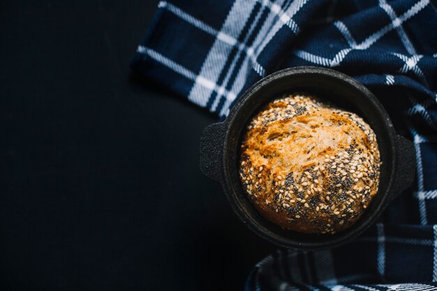 Whole wheat bread with seeds in the black container on black background