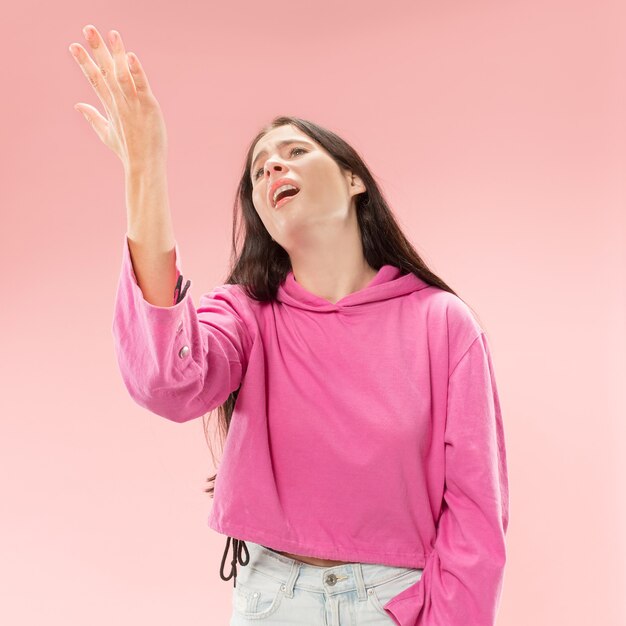 Why is that. Beautiful female half-length portrait isolated on trendy pink studio backgroud. Young emotional surprised, frustrated and bewildered woman. Human emotions, facial expression concept.