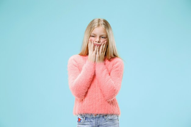 Why is that. Beautiful female half-length portrait on trendy blue studio backgroud. Young emotional surprised, frustrated and bewildered teen girl. Human emotions, facial expression concept.