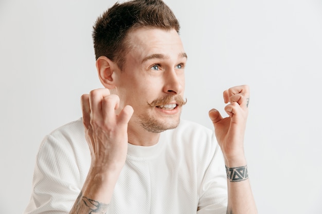 Why is that. Beautiful male half-length portrait isolated on gray studio backgroud. Young emotional surprised, frustrated and bewildered man. Human emotions, facial expression concept.