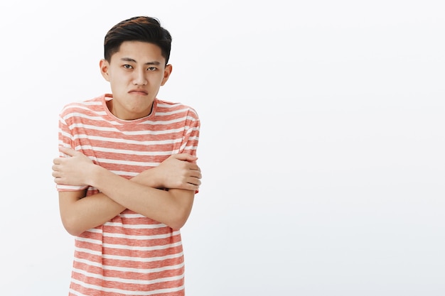 なぜ冷蔵庫のように寒いのですか。ストライプのTシャツに身を包んだ激しいアジアの10代の男
