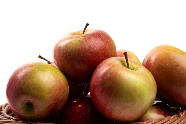 Wicker basket of fresh juicy apples isolated on white.