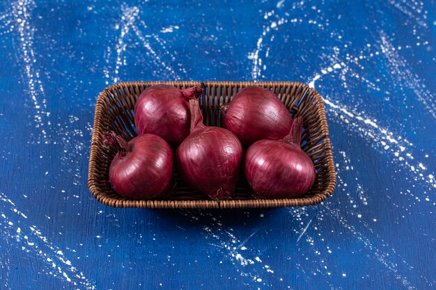 Free photo wicker basket of fresh red onions marble surface