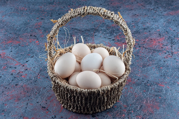 Free photo a wicker basket full of fresh raw chicken eggs
