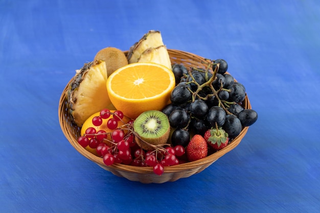 A wicker basket full of fruits on blue surface