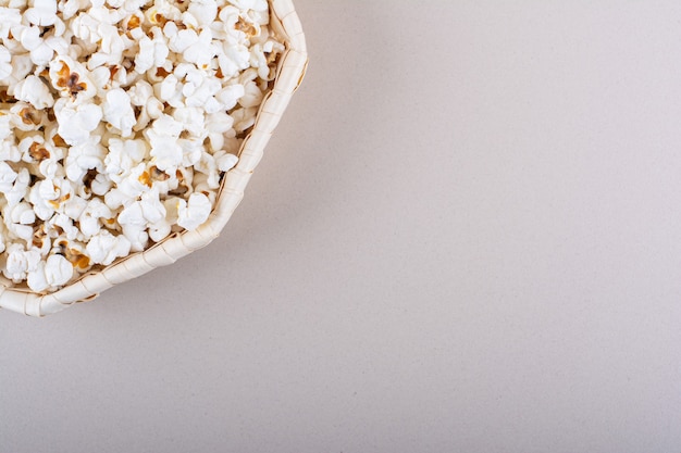 Wicker basket of salted popcorn for movie night on white background. High quality photo