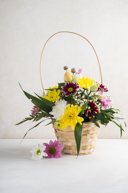 Wicker basket with flowers placed on desk