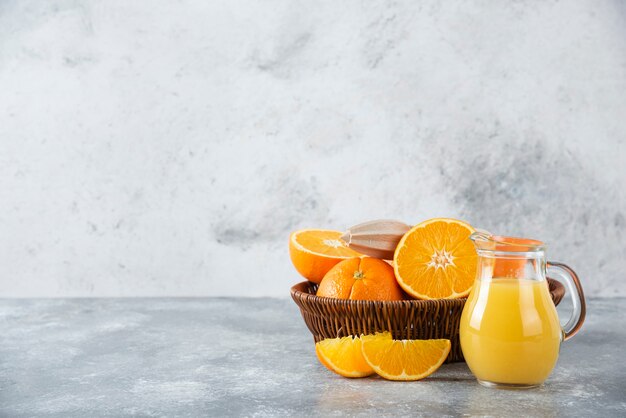 A wicker box full of juicy orange fruits on stone table .