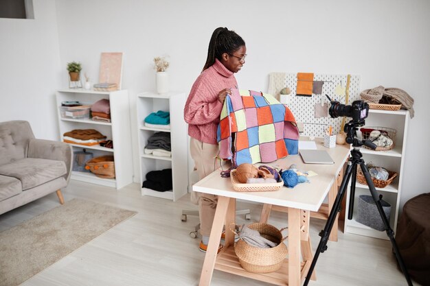 집에서 뜨개질을 하고 비디오나 라이브를 녹화하는 젊은 아프리카계 미국인 여성의 광각 초상화