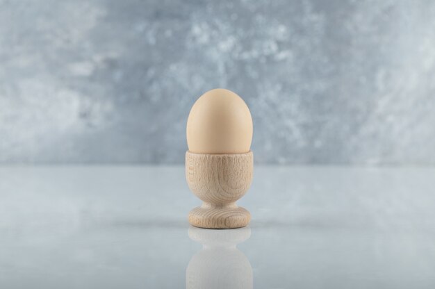 Wide angle photo of Boiled egg in wooden eggcup on white background.