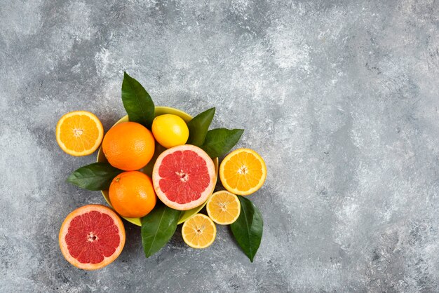 Wide angle photo of Fresh citrus fruits over grey surface. 