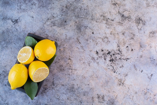 Широкоугольное фото органических лимонов на сером.