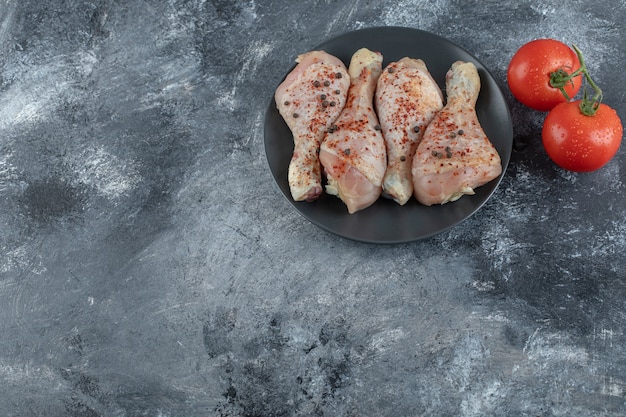 Wide angle photo of raw chicken legs on grey background.