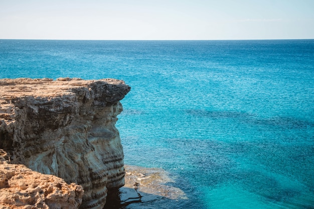 Wide angle shot of a cliff next to the ocean during daytime