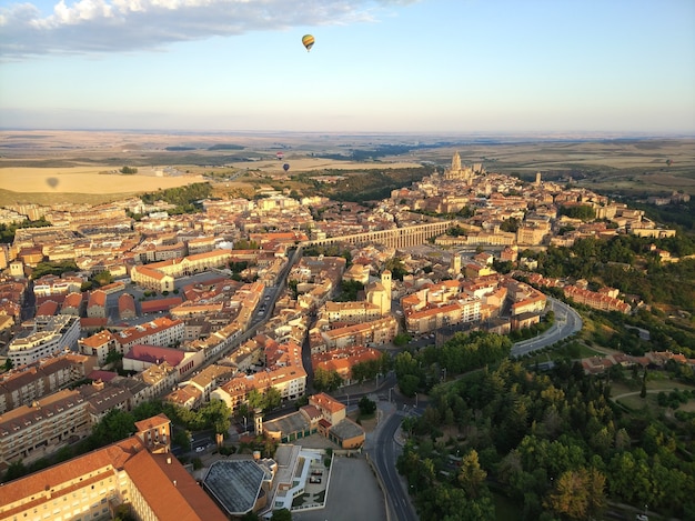 Wide angle shot of many buildings surrounded by trees and a parachute up in the air