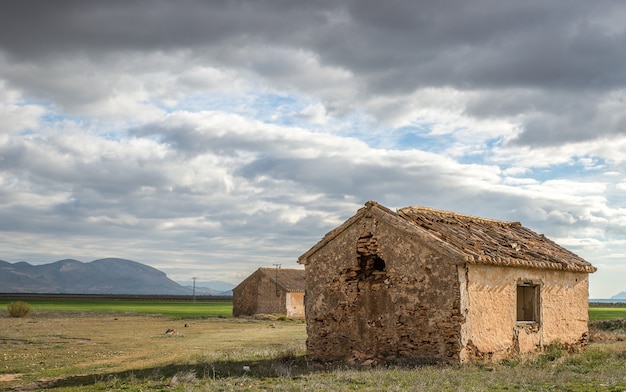 Wide angle shot of old houses on a green field under a cloudy sky