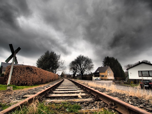 Free photo wide angle shot of the railway tracks surrounded by trees under a clouded sky