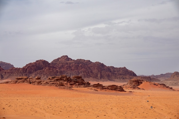 Wide angle shot of several large cliffs on a desert under a cloudy sky