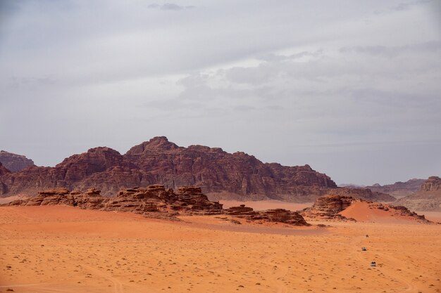Широкоугольный снимок нескольких больших скал в пустыне под облачным небом