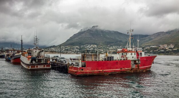 Wide angle shot of several ships on the water behind the mountain under a cloudy sky