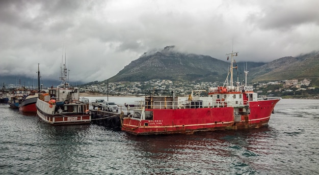 Wide angle shot of several ships on the water behind the mountain under a cloudy sky