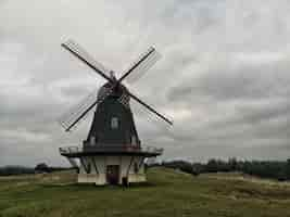 Free photo wide angle shot of a windmill under a sky full of clouds