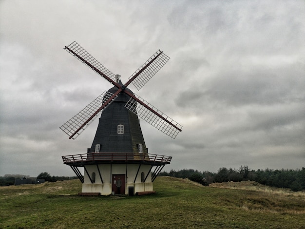 Wide angle shot of a windmill under a sky full of clouds