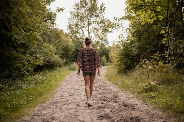 Foto gratuita colpo grandangolare di una donna che cammina attraverso una passerella circondata da alberi