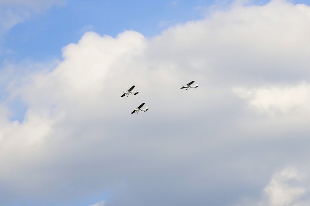 Wide angle sot of three airplanes flying in a triangular pattern behind clouds