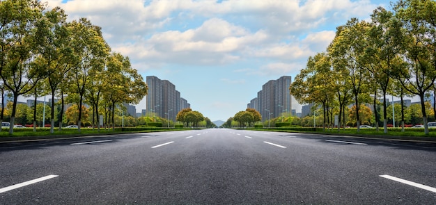 Wide asphalt road with buildings on the horizon