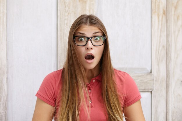 Wide-eyed female student with long fair hair having surprised and forgetful look.