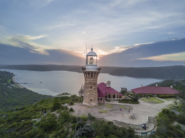 Wide range shot of a lighthouse next to the forest and the sea in Thailand during sunset