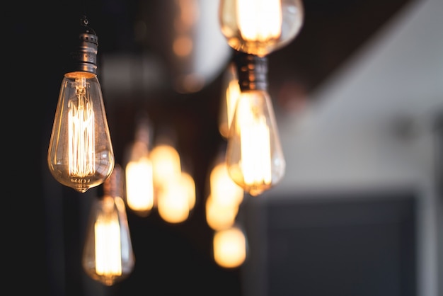 Wide selective closeup shot of illuminated light bulbs hanging from a ceiling