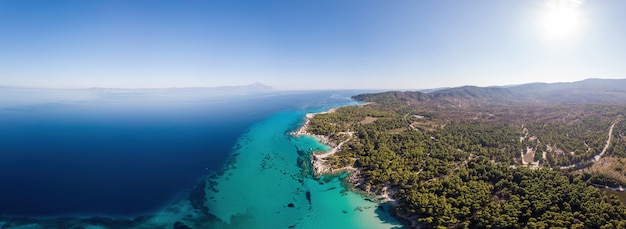 青い透明な水、周りの緑、ドローン、ギリシャからのパモラマの眺めとエーゲ海の海岸のワイドショット