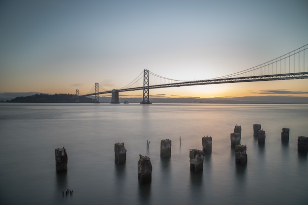 Wide shot of Bay Bridge on the body of water during sunrise in San Francisco, California