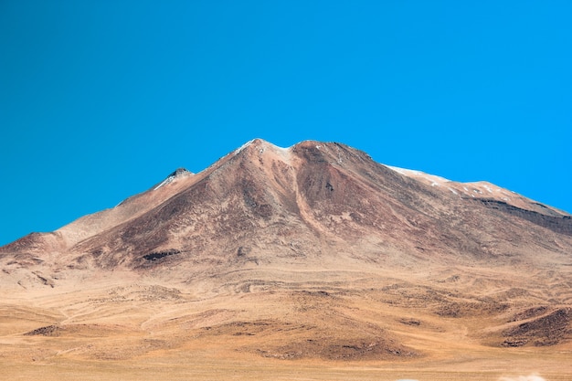 Wide shot of a beautiful mountain surrounded by grassland on a sunny day