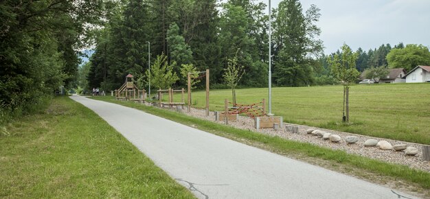 Wide shot of a bike road and a playground near tall trees